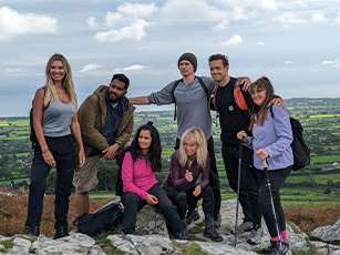 celebrities from the pilgrimage series during a walk on the top of a mound with rolling fields behind them